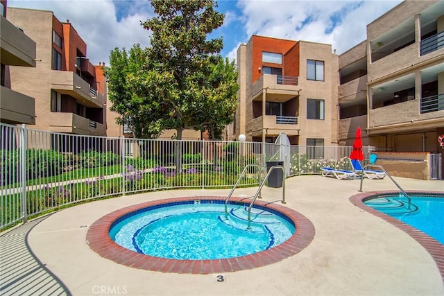 pool featuring fence, a hot tub, and a patio area