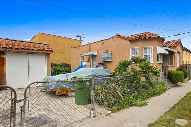 159 E 105th St, Los Angeles, CA 90003 - view of home's exterior featuring a tiled roof, stucco siding, and a gate