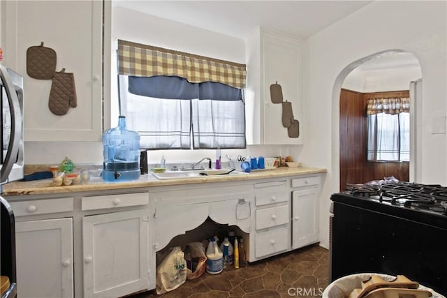 159 E 105th St, Los Angeles, CA 90003 - kitchen with a sink, arched walkways, range with gas cooktop, white cabinets, and light countertops