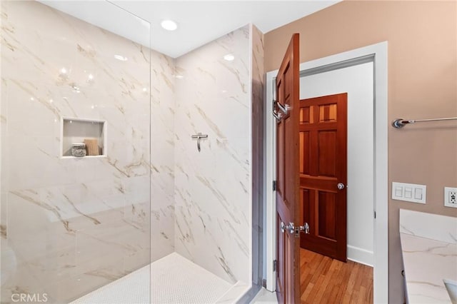 full bathroom with a marble finish shower, wood finished floors, and recessed lighting