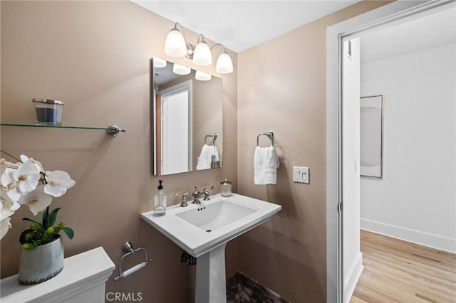 half bath featuring baseboards, wood finished floors, and toilet