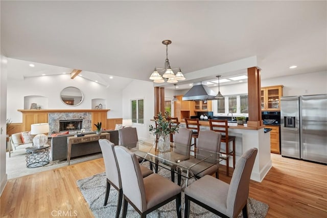 dining area with light wood finished floors, a fireplace, a chandelier, and recessed lighting