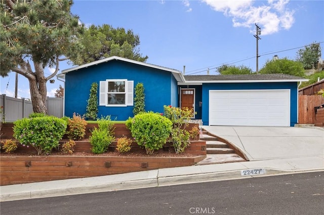 view of front facade with driveway, fence, a garage, and stucco siding