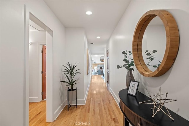 hall featuring light wood-style flooring, recessed lighting, and baseboards