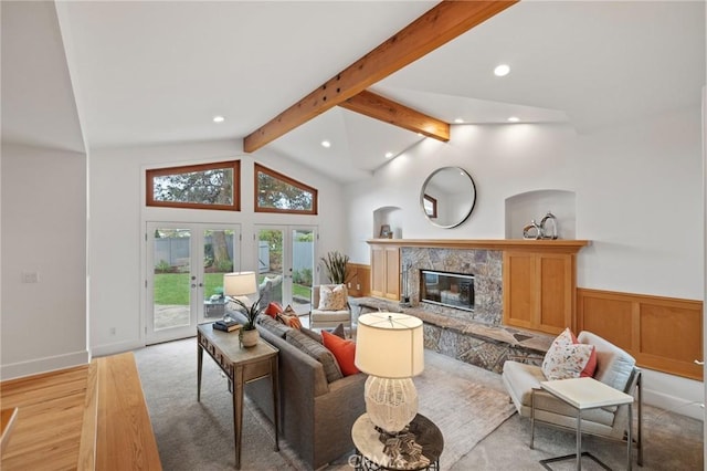 living room featuring recessed lighting, a glass covered fireplace, a wainscoted wall, light wood-type flooring, and french doors