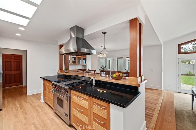 kitchen featuring high end stainless steel range, island range hood, light wood-style floors, pendant lighting, and baseboards