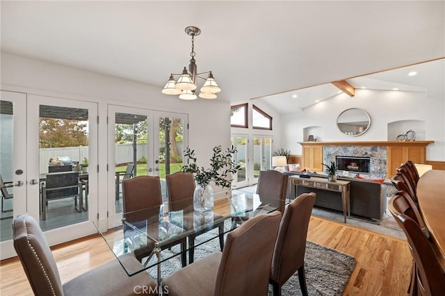 dining area with french doors, a chandelier, light wood-type flooring, a premium fireplace, and recessed lighting