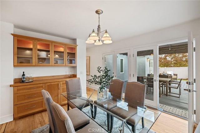 dining space with a chandelier, light wood-style floors, and baseboards
