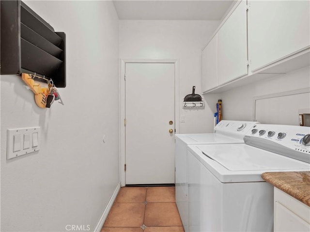 clothes washing area featuring light tile patterned floors, baseboards, cabinet space, and washing machine and clothes dryer