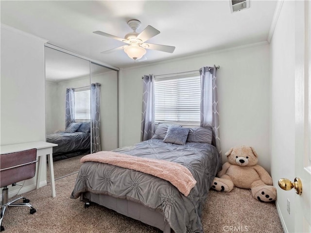 carpeted bedroom featuring a ceiling fan, visible vents, baseboards, a closet, and ornamental molding