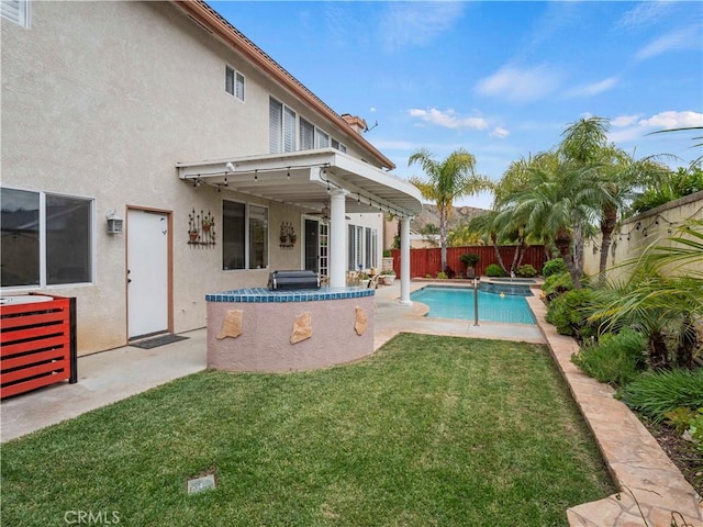 view of pool featuring a patio, a fenced backyard, a pool with connected hot tub, and a yard