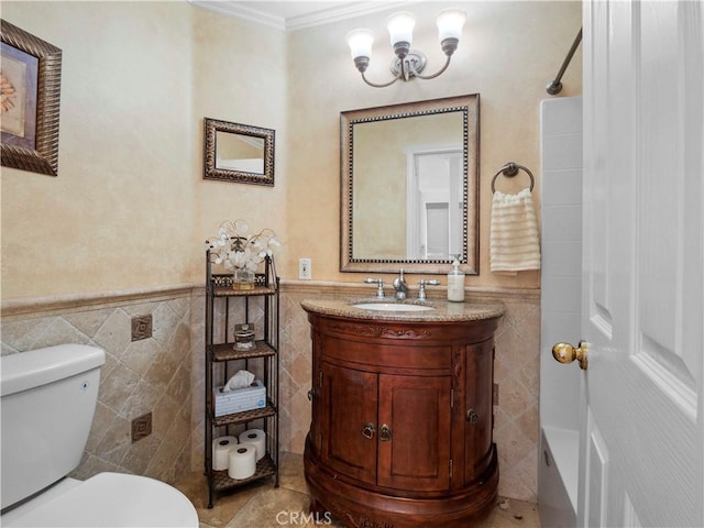 bathroom with an inviting chandelier, ornamental molding, vanity, toilet, and tile walls