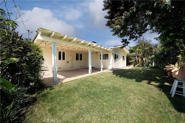 back of house featuring a lawn, a patio, stucco siding, and a pergola