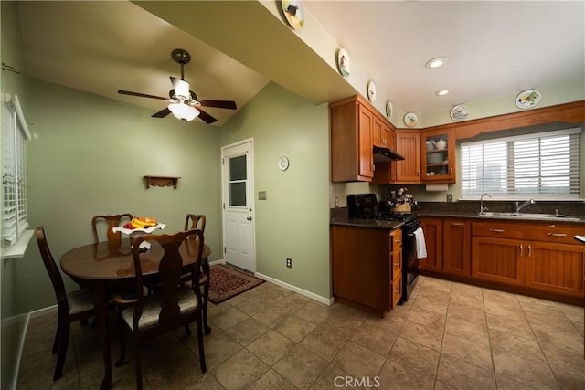 kitchen with a ceiling fan, brown cabinets, a sink, black range with gas stovetop, and glass insert cabinets