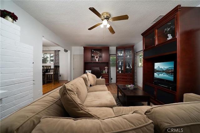 living room featuring a ceiling fan, a textured ceiling, and wood finished floors
