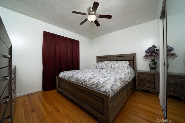 bedroom with baseboards, a ceiling fan, a textured ceiling, and wood finished floors