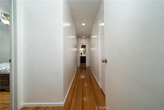 hallway featuring baseboards, recessed lighting, wood finished floors, and visible vents
