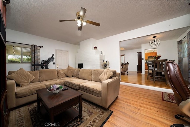 living room featuring a textured ceiling, ceiling fan, and light wood-style flooring