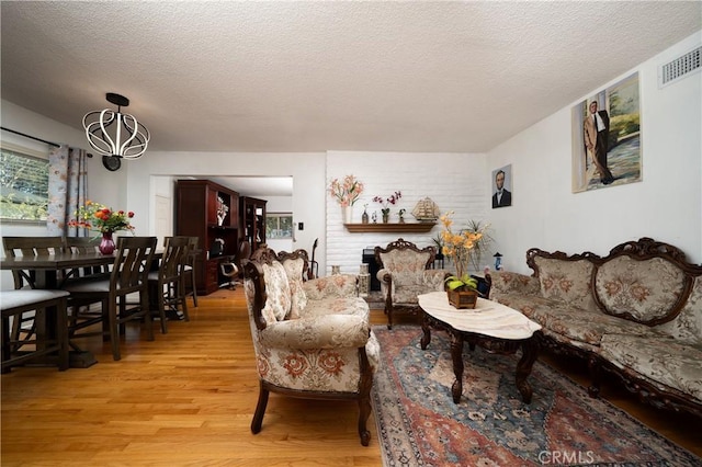 living room with light wood finished floors, a textured ceiling, and visible vents