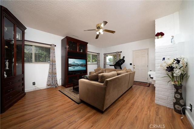 living room featuring baseboards, light wood-style flooring, and ceiling fan