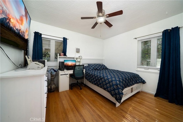 bedroom with a textured ceiling, ceiling fan, and light wood-type flooring