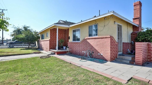 13241 Fairview St, Garden Grove, CA 92843 - rear view of property featuring fence, stucco siding, a chimney, brick siding, and a yard