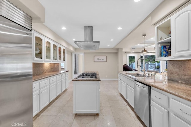 kitchen with island exhaust hood, a sink, appliances with stainless steel finishes, and tasteful backsplash