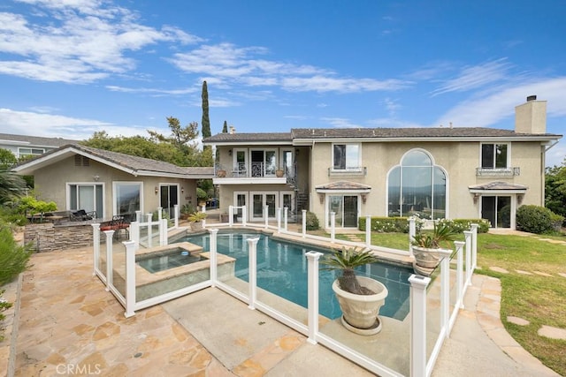 view of pool featuring a lawn, a pool with connected hot tub, french doors, and a patio area