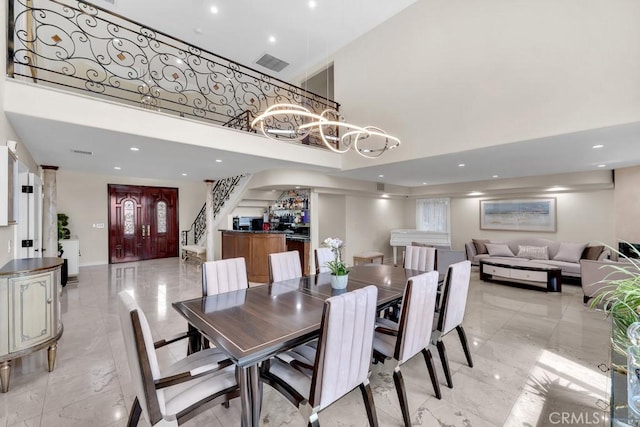 dining area featuring an inviting chandelier, a towering ceiling, recessed lighting, and marble finish floor