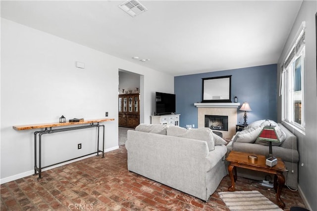 living room with baseboards, brick floor, a fireplace, and visible vents