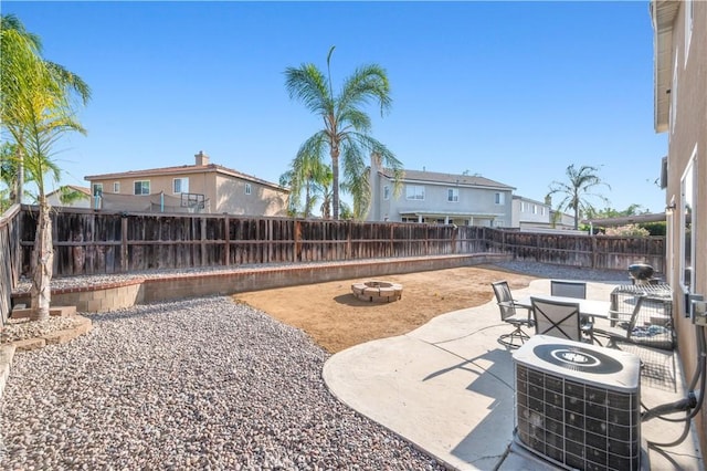 view of yard featuring a fenced backyard, central air condition unit, a fire pit, and a patio area