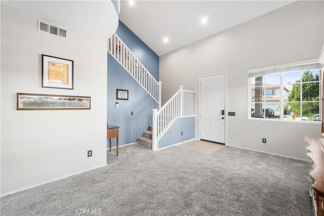 foyer entrance with stairway, visible vents, baseboards, and carpet