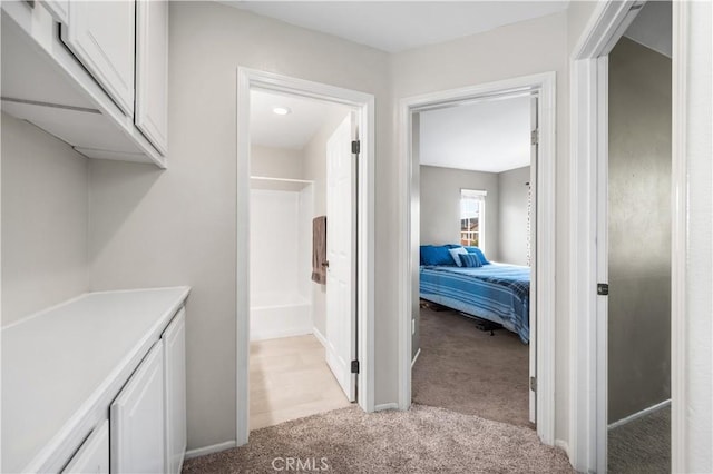 corridor featuring baseboards and light carpet