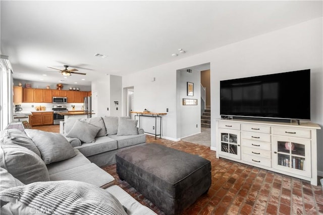 living room featuring baseboards, stairway, recessed lighting, brick floor, and a ceiling fan