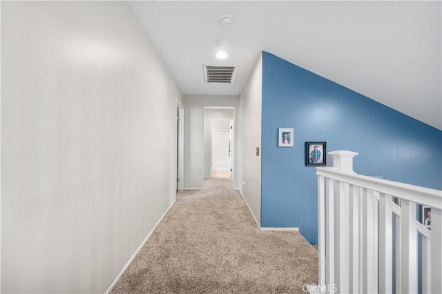 hall featuring carpet flooring, baseboards, visible vents, and an upstairs landing