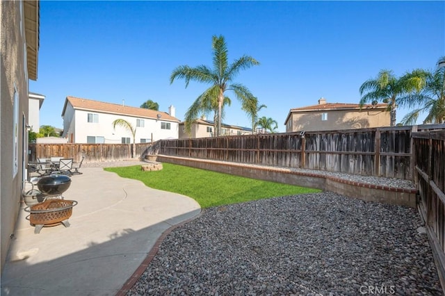 view of yard featuring a patio, a fenced backyard, and a fire pit