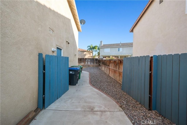 view of property exterior with a fenced backyard, a gate, a patio, and stucco siding