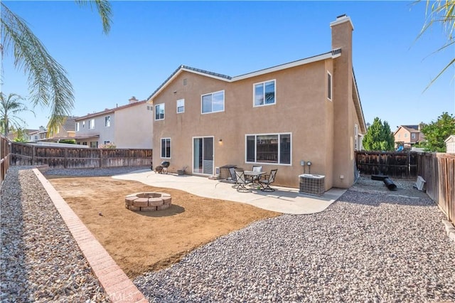 back of house with a chimney, a fire pit, a patio, and stucco siding