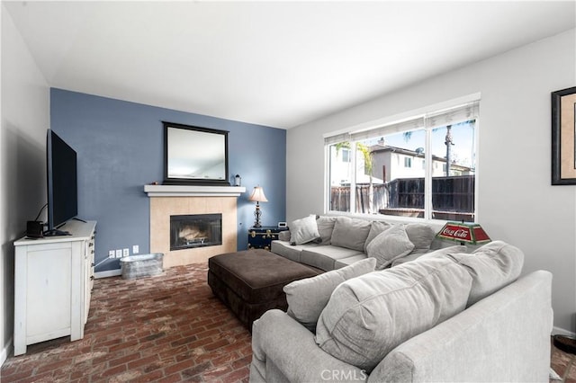 living room featuring a tiled fireplace and brick floor