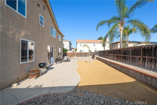 view of patio featuring a fenced backyard, a fire pit, and a residential view