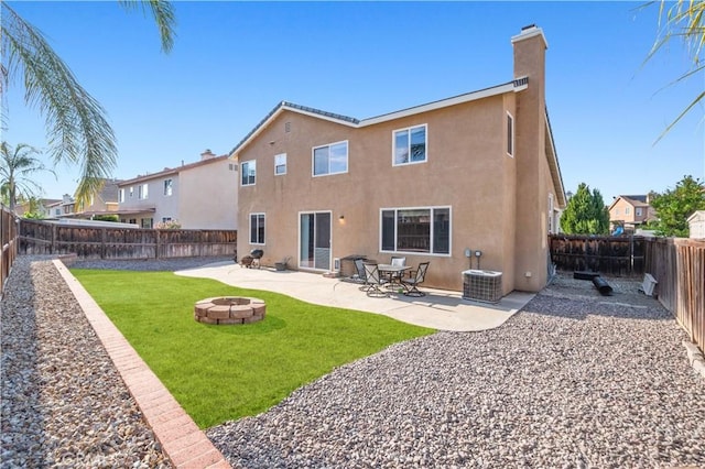 back of property with a lawn, stucco siding, a chimney, and an outdoor fire pit