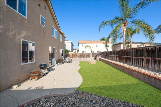 view of yard with a fenced backyard, a fire pit, and a patio area