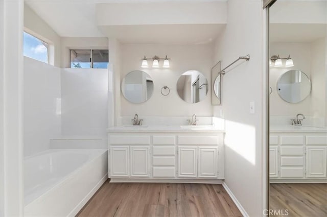 full bath with double vanity, a sink, and wood finished floors
