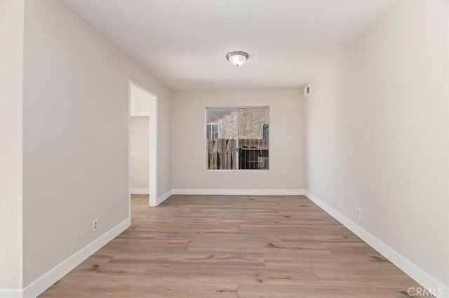 unfurnished room featuring baseboards and light wood-type flooring