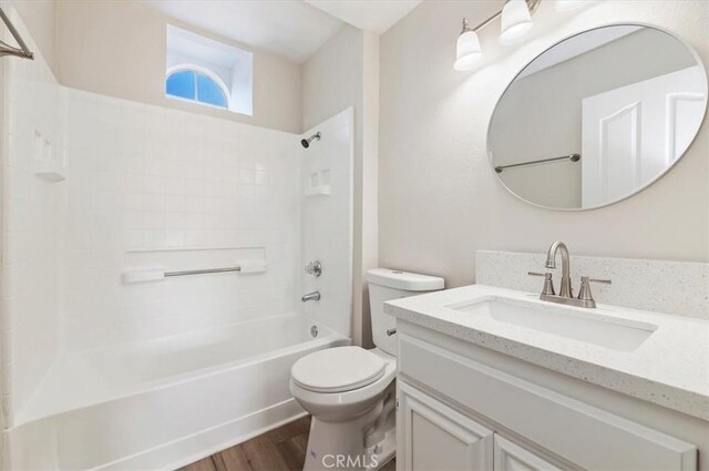 bathroom with washtub / shower combination, vanity, toilet, and wood finished floors