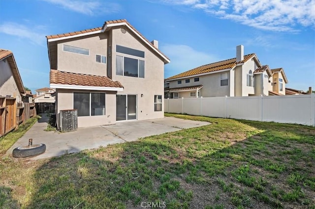rear view of property featuring a fenced backyard, stucco siding, a patio area, a tiled roof, and a yard