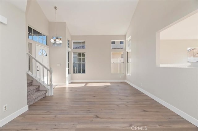 entryway featuring an inviting chandelier, baseboards, stairs, and wood finished floors