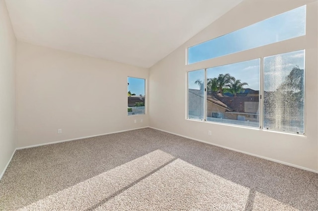 carpeted spare room featuring baseboards, a wealth of natural light, and lofted ceiling
