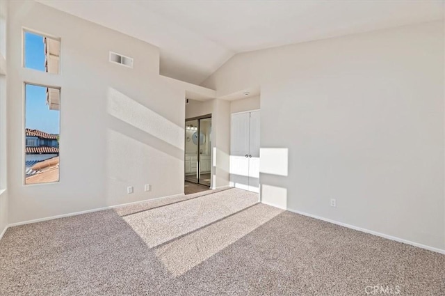 carpeted spare room featuring baseboards, visible vents, and vaulted ceiling