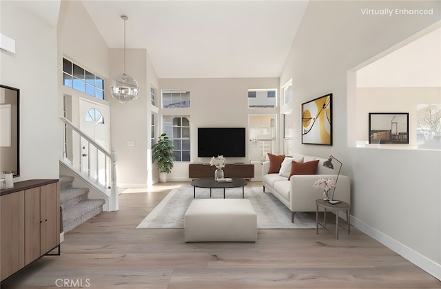 living room with high vaulted ceiling, baseboards, light wood-type flooring, and stairs